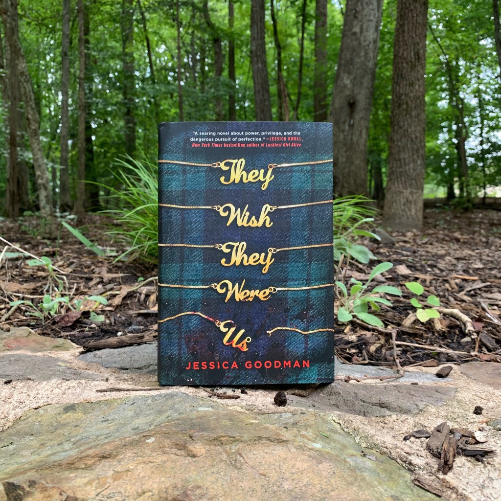 They Wish They Were Us by Jessica Goodman hardcover in the woods