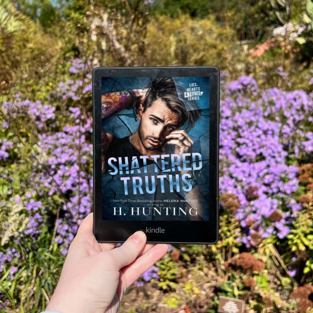 Photo of H Hunting's Shattered Truths on Kindle in front of purple flowers